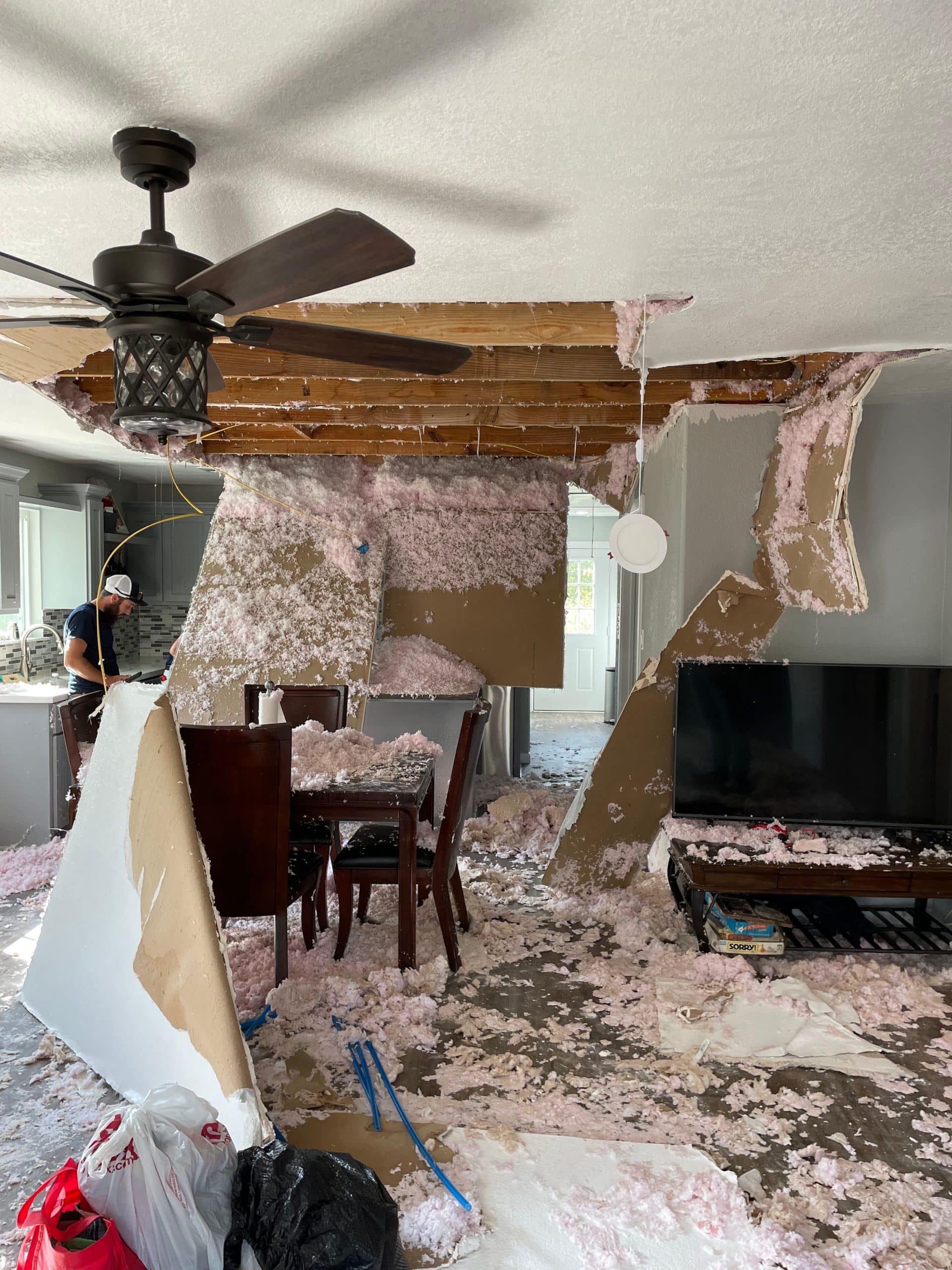 Water damage restoration in progress, with removed drywall, insulation, and debris in a living room following water damage.